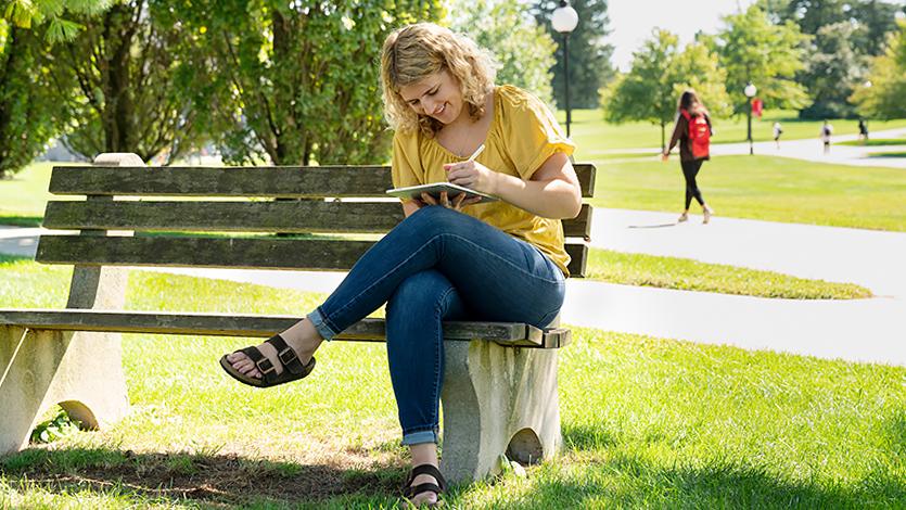 Image of student working outside on a sunny day.